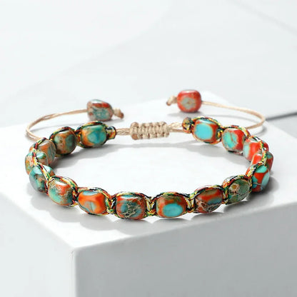 Turquoise and orange stone beaded adjustable woven bracelet on white surface
