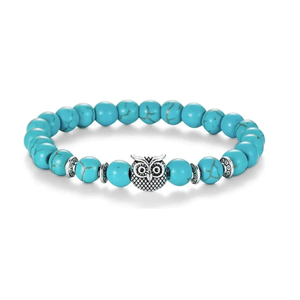 Turquoise beaded bracelet with silver owl charm and decorative silver spacers on a white background