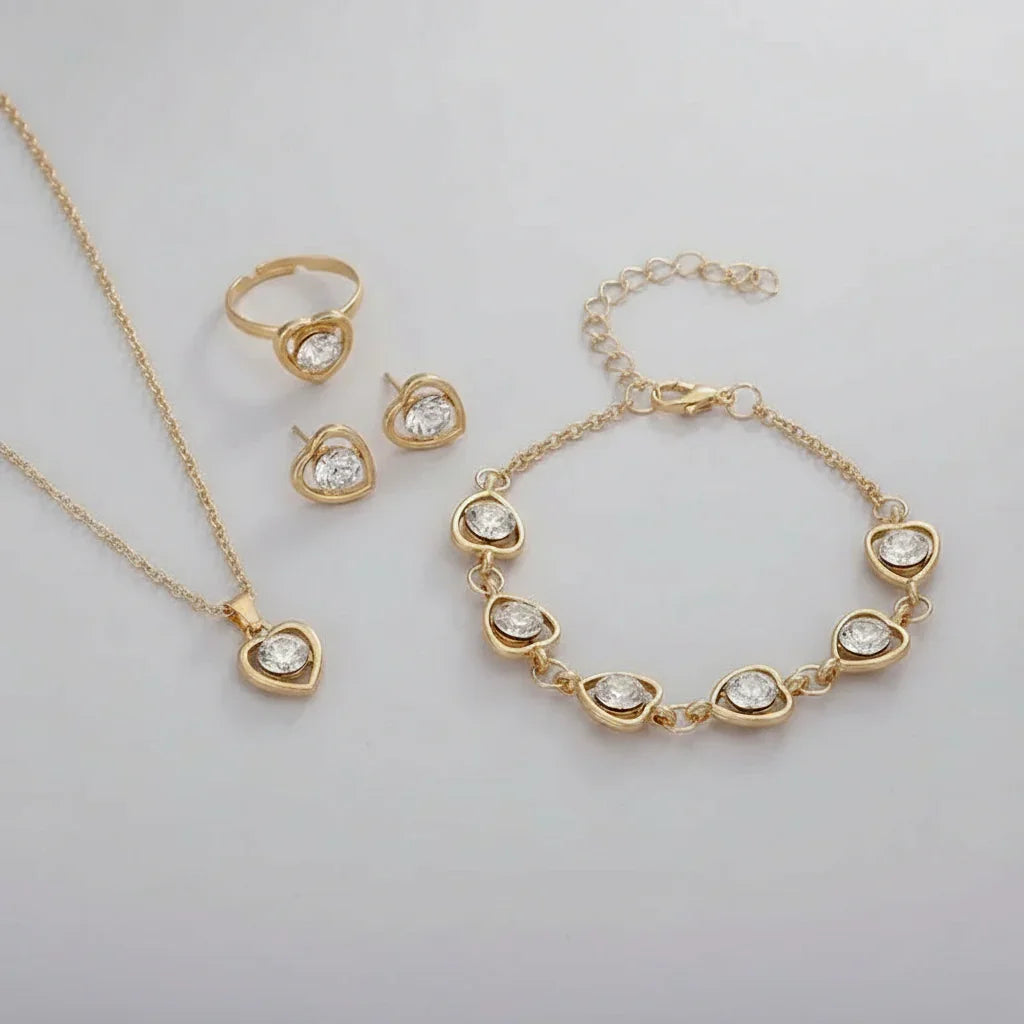 Gold heart-shaped jewelry set with clear gemstones including necklace, ring, earrings, and bracelet on white
