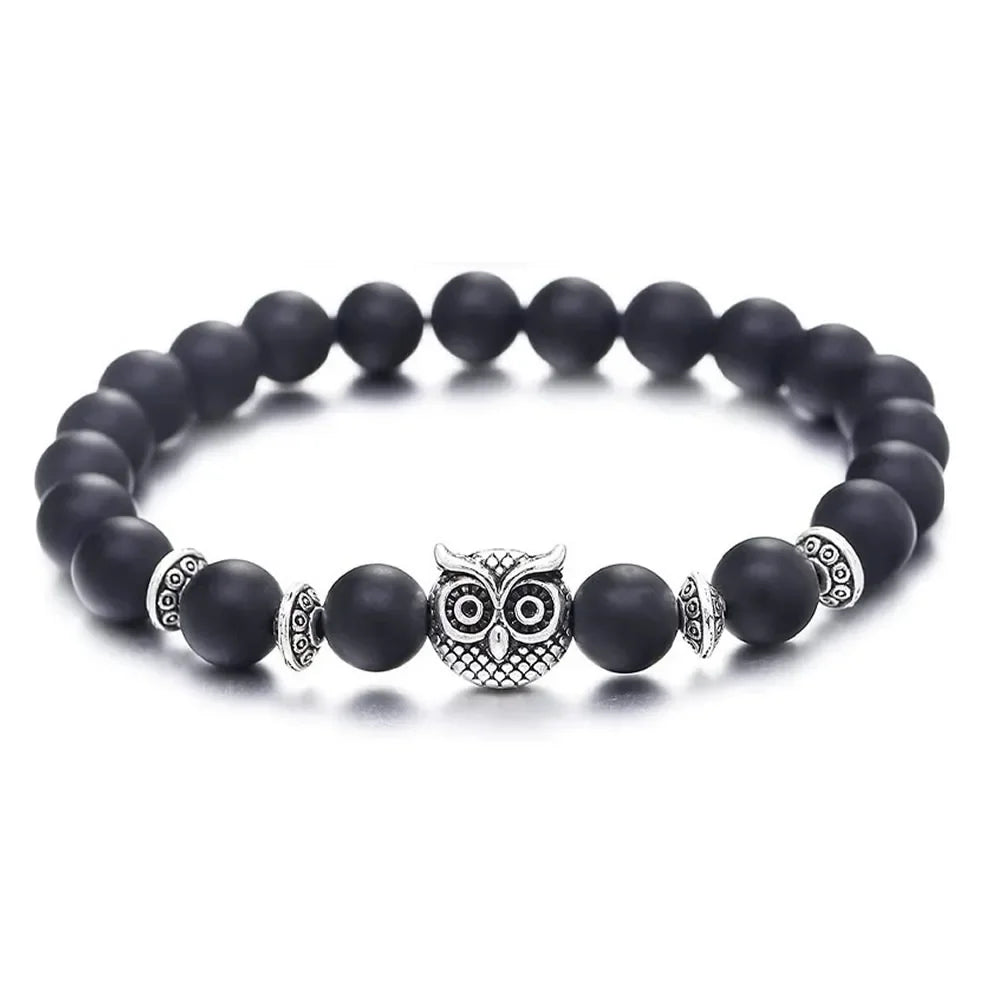 Black beaded bracelet with silver owl charm and decorative spacers on white background