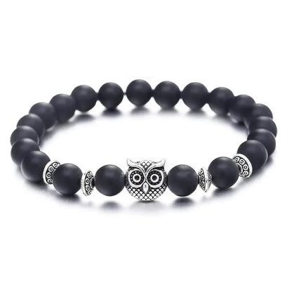 Black beaded bracelet with silver owl charm and decorative spacers on white background