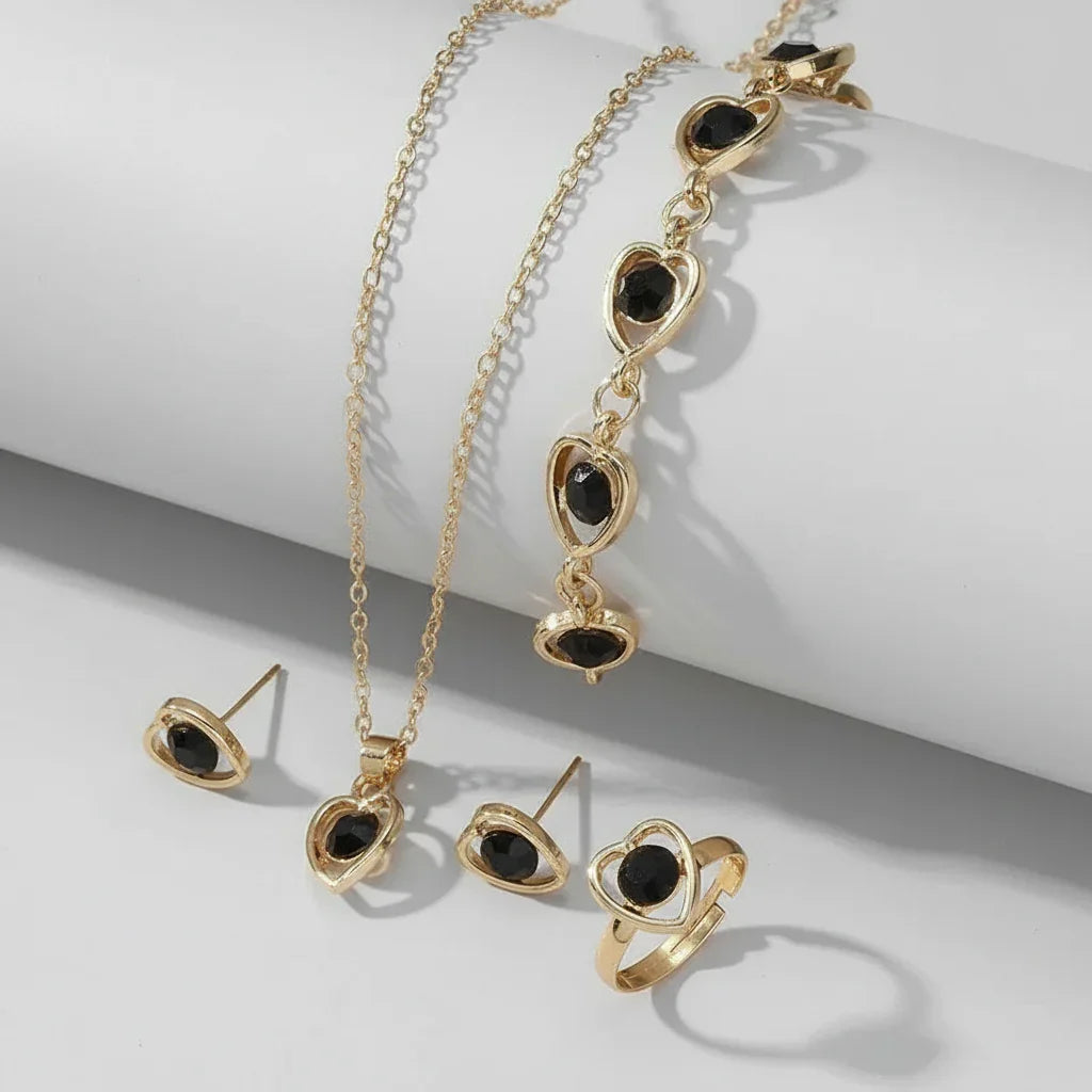 Gold jewelry set with black gemstone heart-shaped pendant necklace, bracelet, ring, and earrings