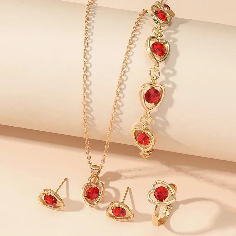 Gold jewelry set with red heart-shaped gemstones including necklace, bracelet, earrings, and ring