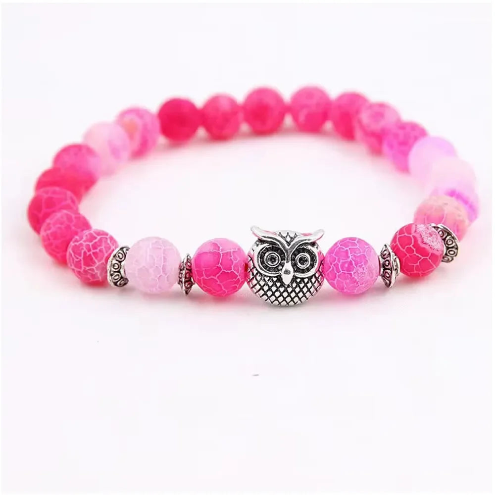 Pink beaded bracelet with a silver owl charm and decorative silver spacers on a white background